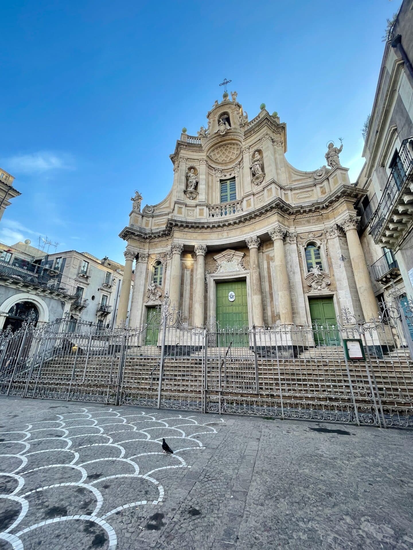 A grand baroque church facade in Catania with intricate architectural details and statues.