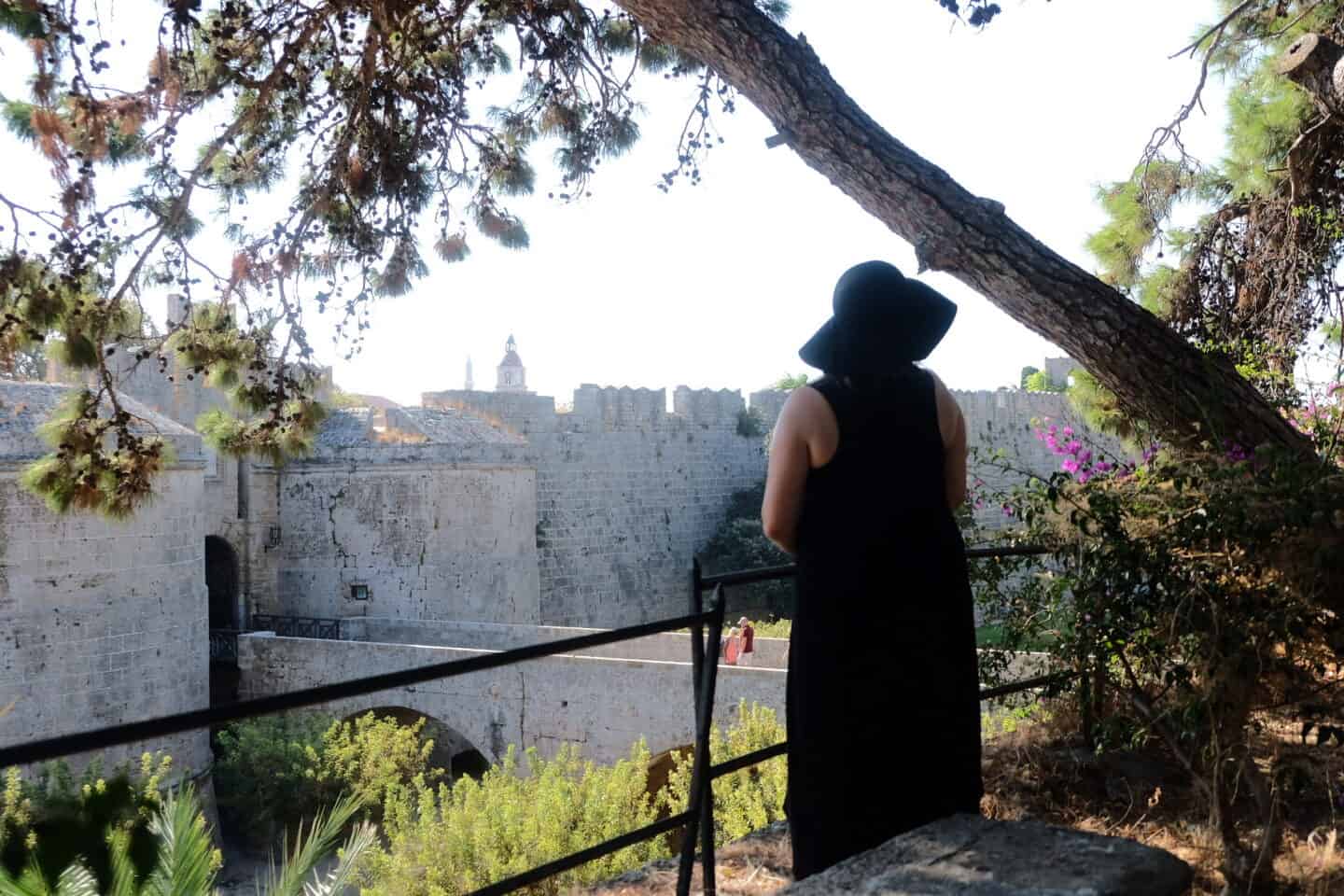 A woman standing alone looking at a castle in greece. How to heal a broken heart with travel